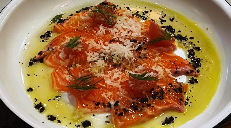 Fishmonger's steelhead crudo is topped with black garlic oil and pickled cherry tomatoes. Henri Hollis/henri.hollis@ajc.com