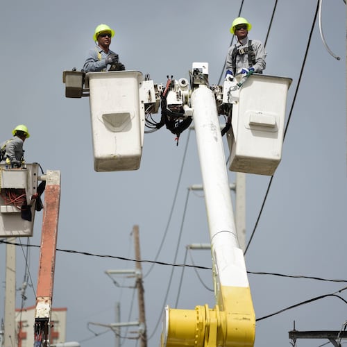 FILE - Puerto Rico Electric Power Authority workers repair distribution lines damaged by Hurricane Maria in the Cantera community of San Juan, Puerto Rico, Oct. 19, 2017. (AP Photo/Carlos Giusti, File)