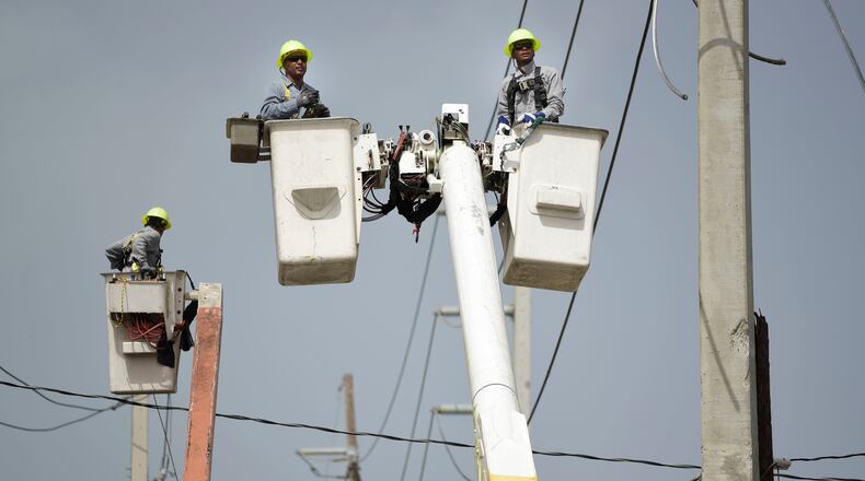 FILE - Puerto Rico Electric Power Authority workers repair distribution lines damaged by Hurricane Maria in the Cantera community of San Juan, Puerto Rico, Oct. 19, 2017. (AP Photo/Carlos Giusti, File)