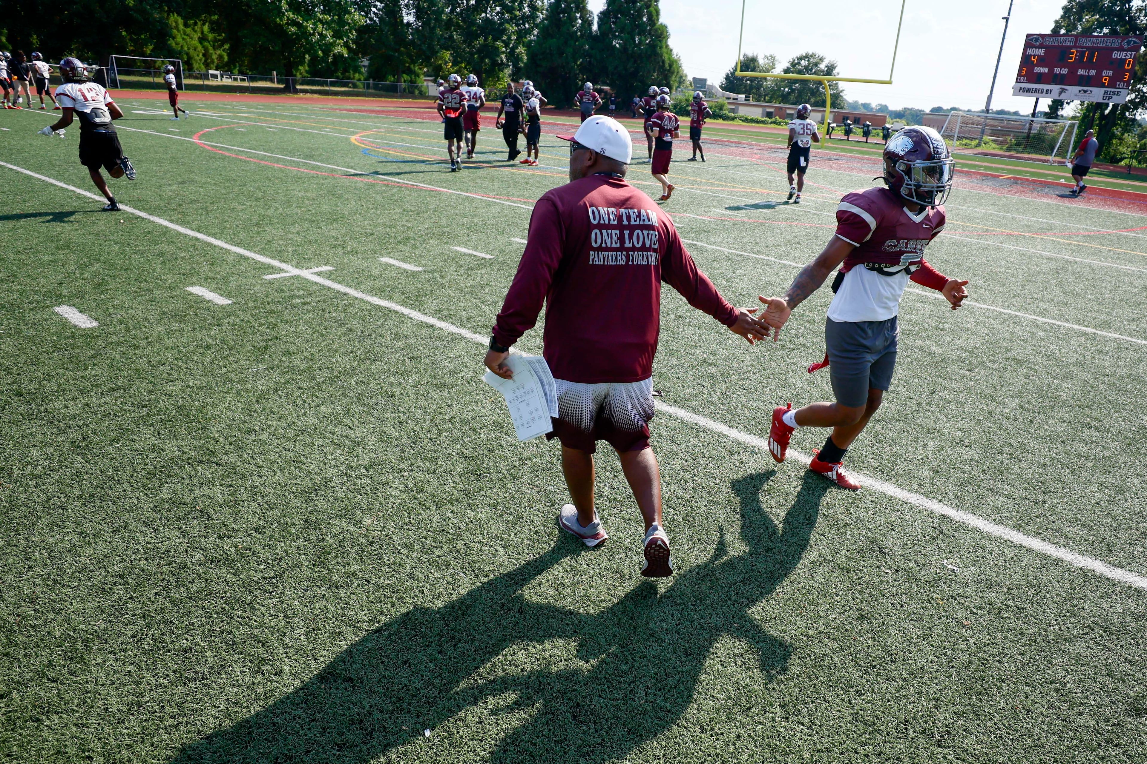 "One team, one love" is more than a saying on Carver High School football coach Darren Myles' sweatshirt. Myles works to create good people, not just good players. (Miguel Martinez/AJC)