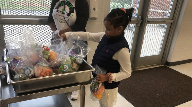 Lily Lambert, 7, picks up food distributed Monday at North Clayton Middle School.
