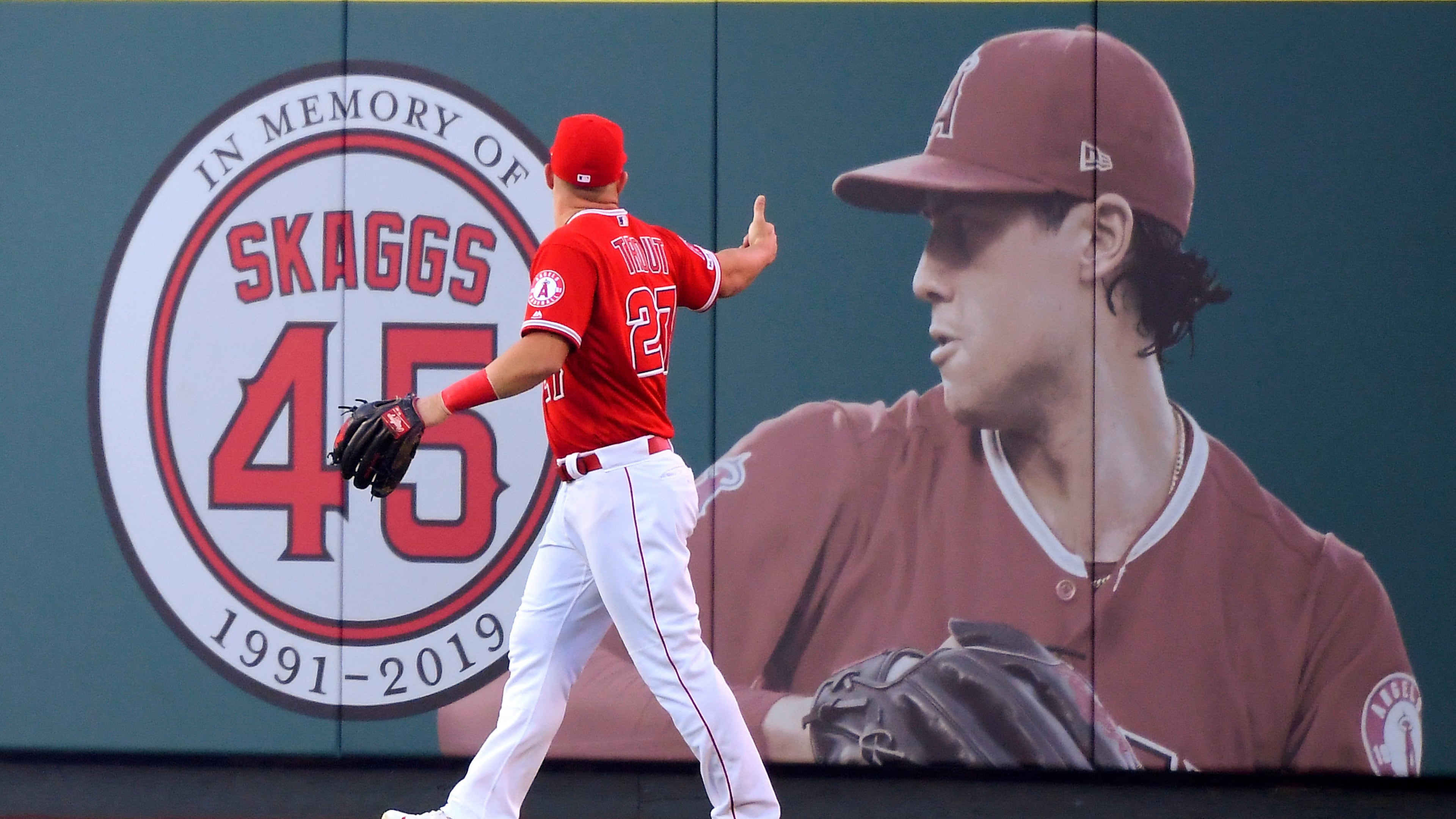 FILE - Los Angeles Angels center fielder Mike Trout gestures toward a photo of Tyler Skaggs in center field prior to a baseball game against the Detroit Tigers in Anaheim, Calif., on July 29, 2019. (AP Photo/Mark J. Terrill, File)