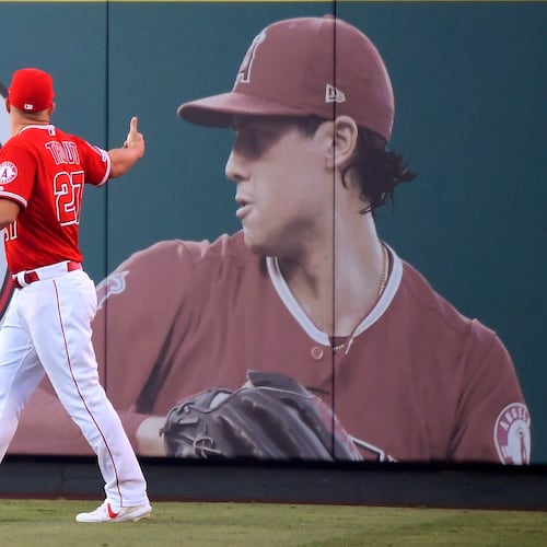FILE - Los Angeles Angels center fielder Mike Trout gestures toward a photo of Tyler Skaggs in center field prior to a baseball game against the Detroit Tigers in Anaheim, Calif., on July 29, 2019. (AP Photo/Mark J. Terrill, File)