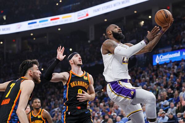 Los Angeles Lakers forward LeBron James, right, looks to score in front of Oklahoma City Thunder guard Alex Caruso, center, and forward Chet Holmgren (7) during the first half of an NBA basketball game Sunday, April 6, 2025, in Oklahoma City. (AP Photo/Nate Billings)
