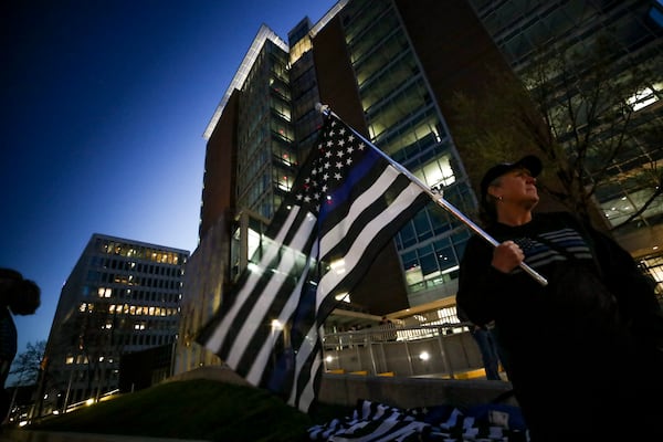 Sally R. of Holland holds a "blue line" flag outside the Kent County Courthouse on the first day of testimony in the 2nd degree murder trial of former Grand Rapids City Police officer Christopher Schurr on April 28, 2025 in Grand Rapids, MI. Schurr shot and killed Congolese immigrant Patrick Lyoya during a traffic stop three years ago. (Chris duMond/Detroit News via AP)