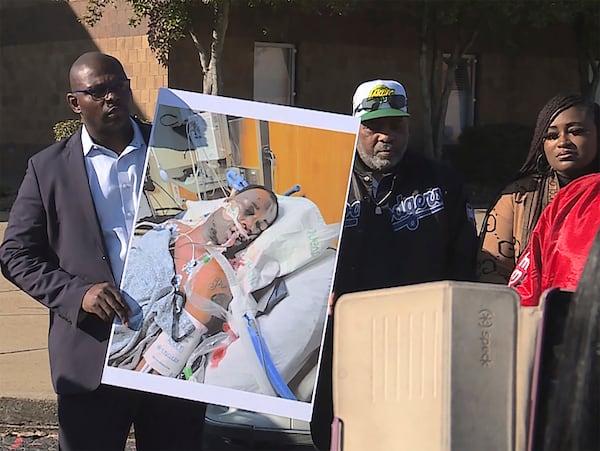 FILE - In this photo provided by WREG, Tyre Nichols' stepfather Rodney Wells, center, stands next to a photo of Nichols in the hospital after his arrest, during a protest in Memphis, Tenn., Jan. 14, 2023. (Jordan James/WREG via AP)