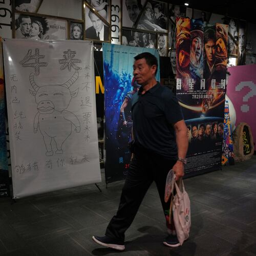 A man walks by a drawing poster promoting a Chinese animated film "Niulai" on display with other movie posters at a cinema in Beijing, Tuesday, Aug. 18, 2026. (AP Photo/Andy Wong)