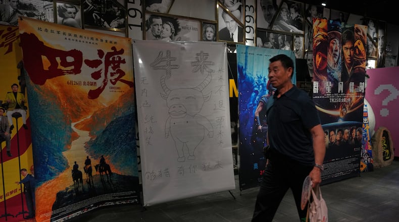 A man walks by a drawing poster promoting a Chinese animated film "Niulai" on display with other movie posters at a cinema in Beijing, Tuesday, Aug. 18, 2026. (AP Photo/Andy Wong)