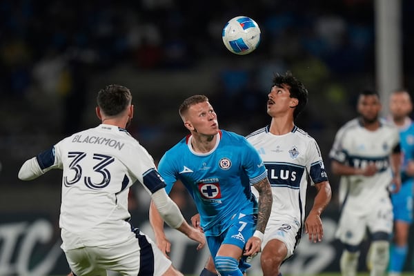 Mateusz Bogusz of Mexico's Cruz Azul, center, competes for the ball against Mathias Laborda, right, and Tristan Blackmon of Canada's Vancouver Whitecaps during the CONCACAF Champions Cup final soccer match in Mexico City, Sunday, June 1, 2025. (AP Photo/Fernando Llano)