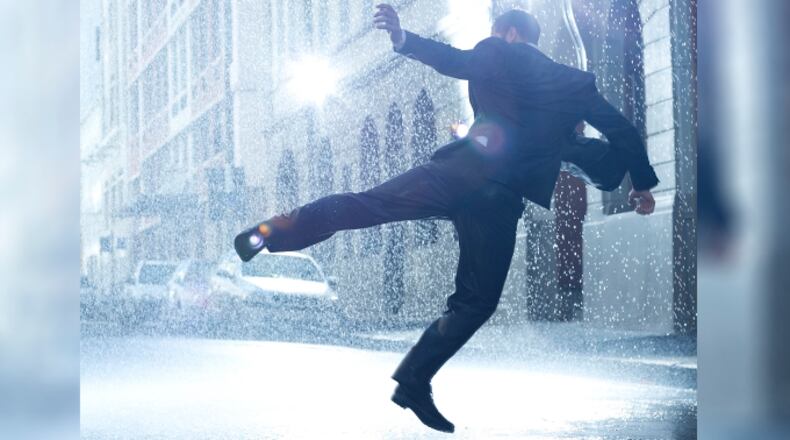 Businessman dancing in rainy street (stock photo)