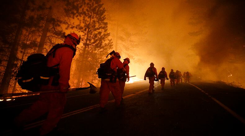 Inmate firefighters walk along Highway 120 after a burnout operation as firefighters continue to battle the Rim Fire near Yosemite National Park, Calif., on Sunday, Aug. 25, 2013. Fire crews are clearing brush and setting sprinklers to protect two groves of giant sequoias as a massive week-old wildfire rages along the remote northwest edge of Yosemite National Park. (AP Photo/Jae C. Hong)