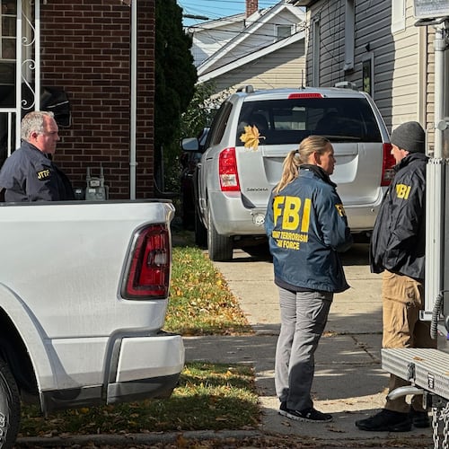 FBI agents gather outside a home in a Dearborn, Mich., neighborhood on Friday, Oct. 31, 2025. (AP Photo/Mike Householder)