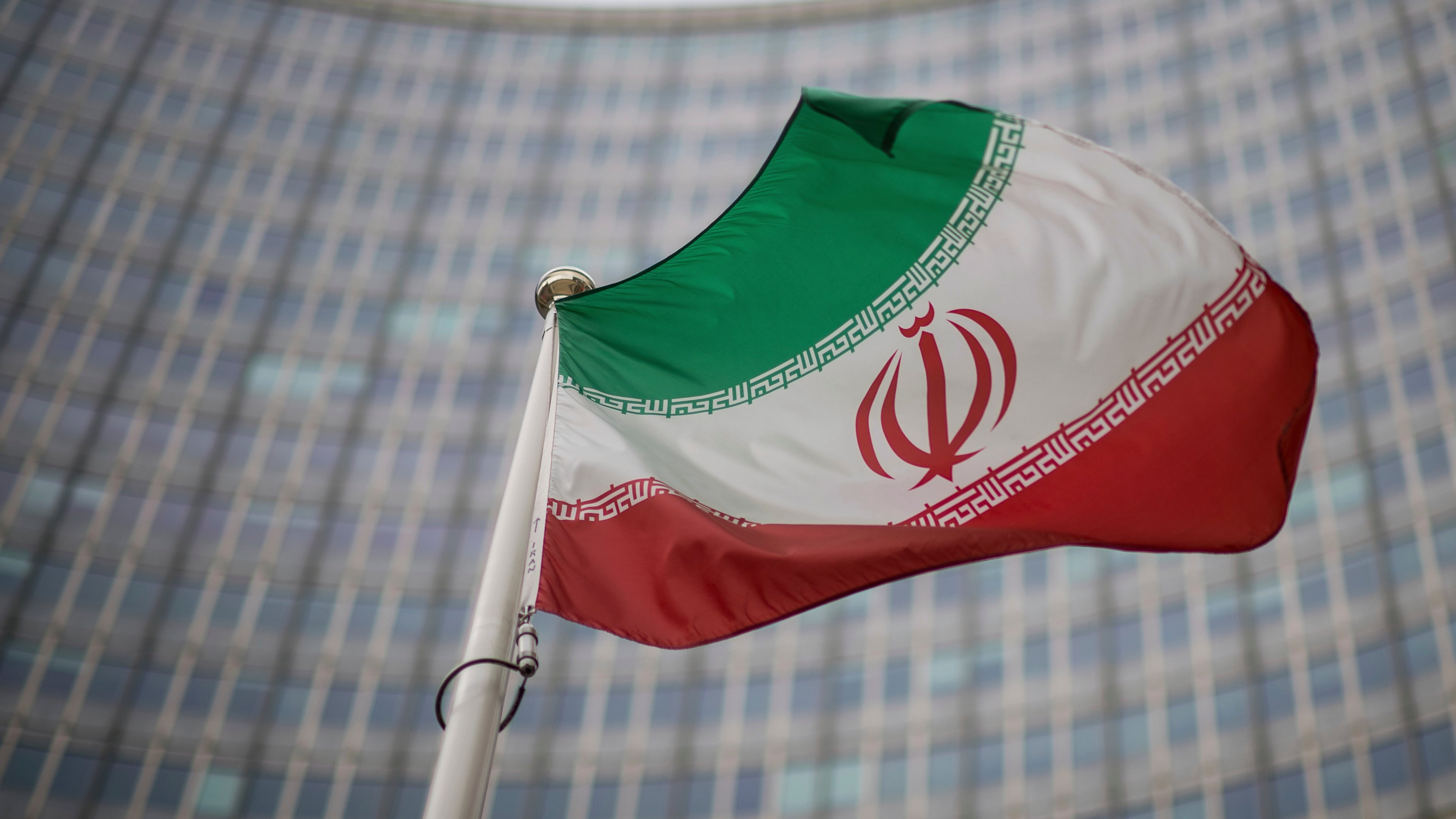 FILE -A national flag of Iran waves in front of the building of the International Atomic Energy Agency, IAEA, in Vienna, Austria, Dec. 17, 2021. (AP Photo/Michael Gruber, File)