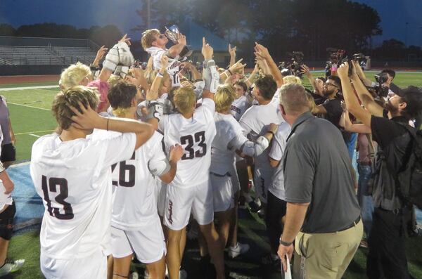 Members of the Lambert Longhorns boys lacrosse team celebrate upon receiving the GHSA Division III championship trophy Friday, May 16, 2025, at Denmark High in Alpharetta. The Longhorns defeated the South Forsyth War Eagles 12-0 for their seventh title, tying them with Westminster for the most boys championships in GHSA history.
