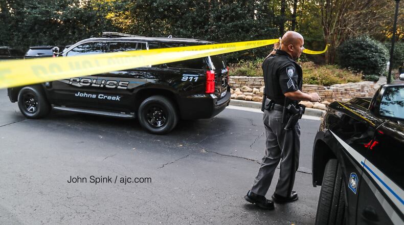 Investigators return to a crime scene at the Retreat at Johns Creek apartments Wednesday after police said new evidence suggests a Monday night shooting could be connected to a body found inside a burning car  in Gwinnett County on Tuesday.