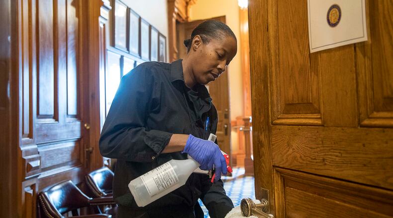 Custodian Brenda Love cleans the door handles at the Georgia Capitol earlier this month. Love said she cleaned “everything the public touches” out of caution due to the coronavirus. (ALYSSA POINTER/ALYSSA.POINTER@AJC.COM)