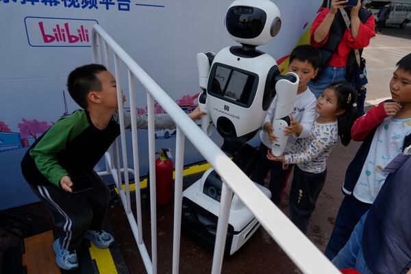 Children react to a wheeled robot after the Humanoid Robot Half-Marathon held in Beijing on Saturday, April 19, 2025. (AP Photo/Ng Han Guan)