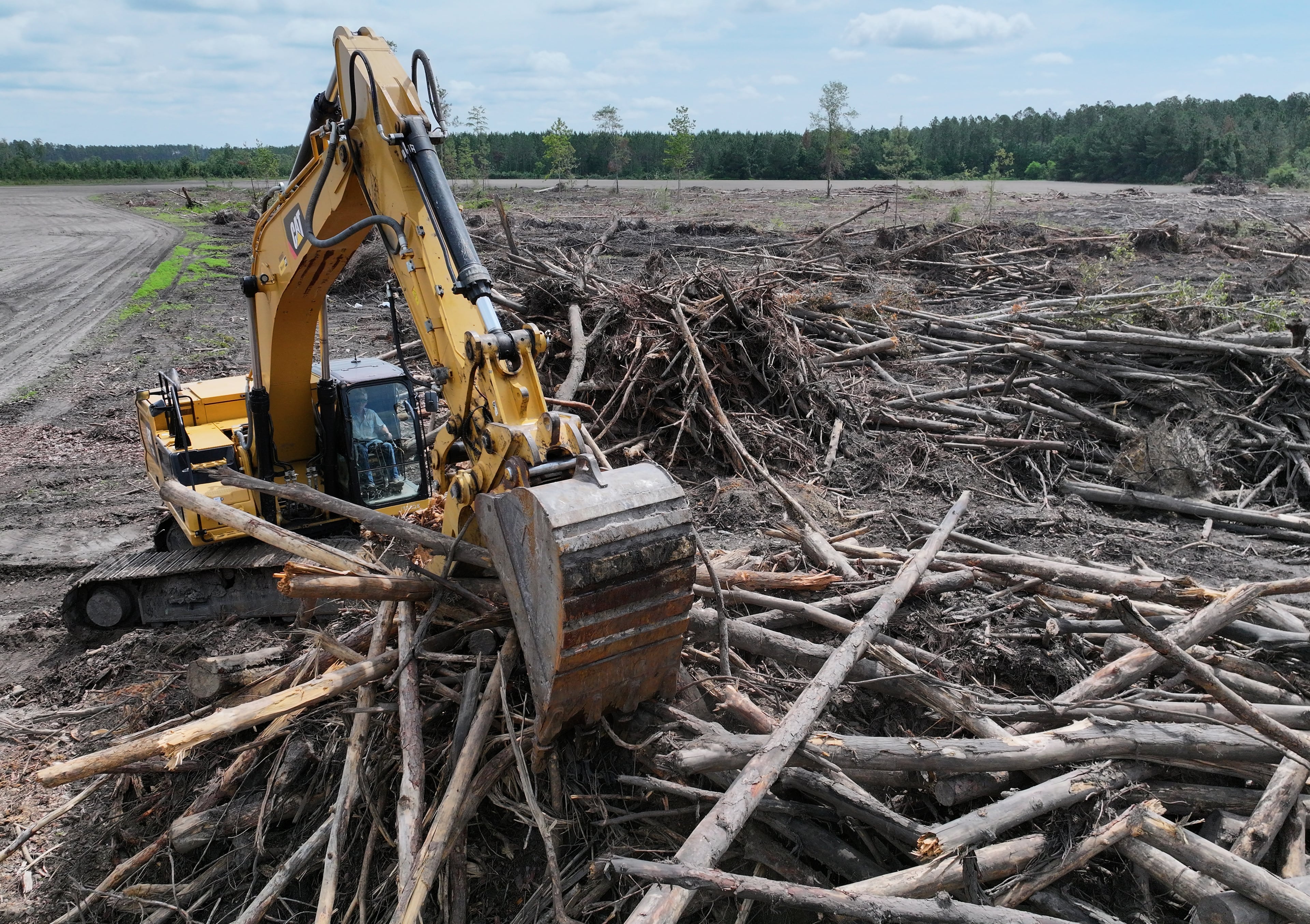 Evan Walker cleans up debris from downed trees on the property of Walker Farms in Wilsonville. Mounds of tree debris lie scattered along South Georgia’s two-lane highways, waiting to be hauled to mills to be processed. Sitting for months, some timber is rotting and worthless. (Hyosub Shin/AJC)