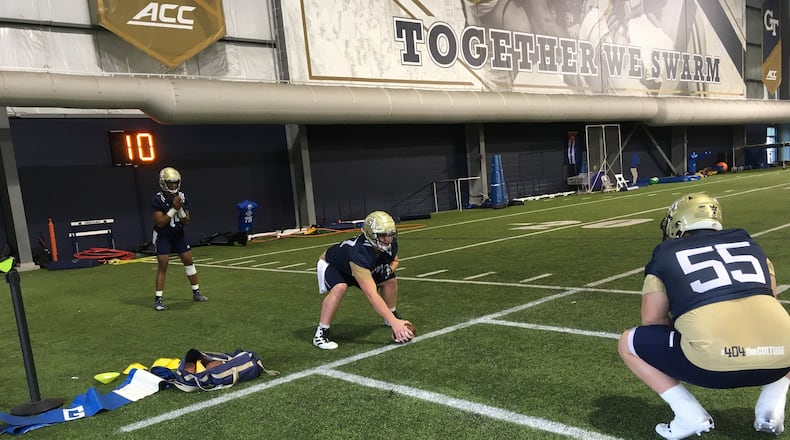 Georgia Tech offensive lineman Mikey Minihan works on his shotgun snaps with quarterback James Graham under the eye of center Kenny Cooper (No. 55) at the Yellow Jackets' first spring practice, March 3, 2020, at the Brock Football Practice Facility. (AJC photo by Ken Sugiura)
