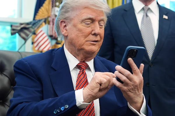 President Donald Trump silences his mobile phone which rang two times as he was speak to reporters after signing executive orders regarding nuclear energy in the Oval Office of the White House, Friday, May 23, 2025, in Washington. (AP Photo/Evan Vucci)