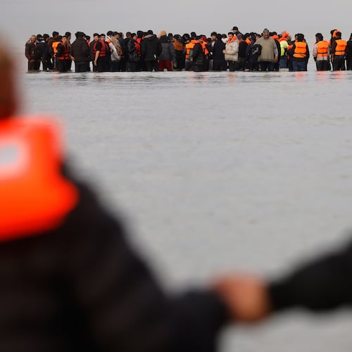 Migrants push a small boat in an attempt to reach Britain, Thursday, Nov. 6, 2025 in Gravelines, northern France. (AP Photo/Jean-Francois Badias)