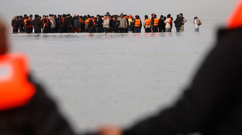 Migrants push a small boat in an attempt to reach Britain, Thursday, Nov. 6, 2025 in Gravelines, northern France. (AP Photo/Jean-Francois Badias)