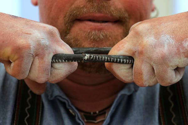 A competitor warms up for his bout while he try to pull the opponent over the table at the German Championships in Fingerhakeln or finger wrestling, in Pang, near Rosenheim, Germany, Sunday, April 27, 2025. (AP Photo/Matthias Schrader)