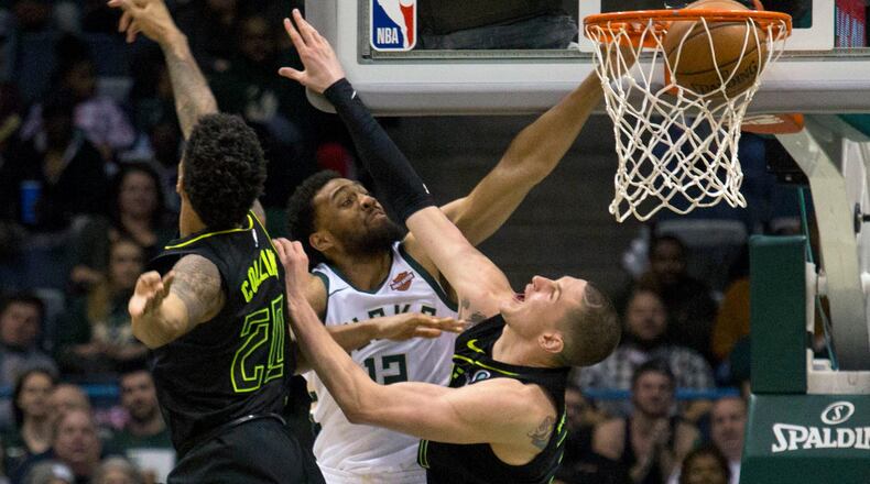 Milwaukee Bucks forward Jabari Parker, center, gets a slam dunk against Atlanta Hawks forward John Collins, left, and Mike Muscala, right, during the second half of an NBA basketball game Tuesday, Feb. 13, 2018, in Milwaukee. (AP Photo/Darren Hauck)