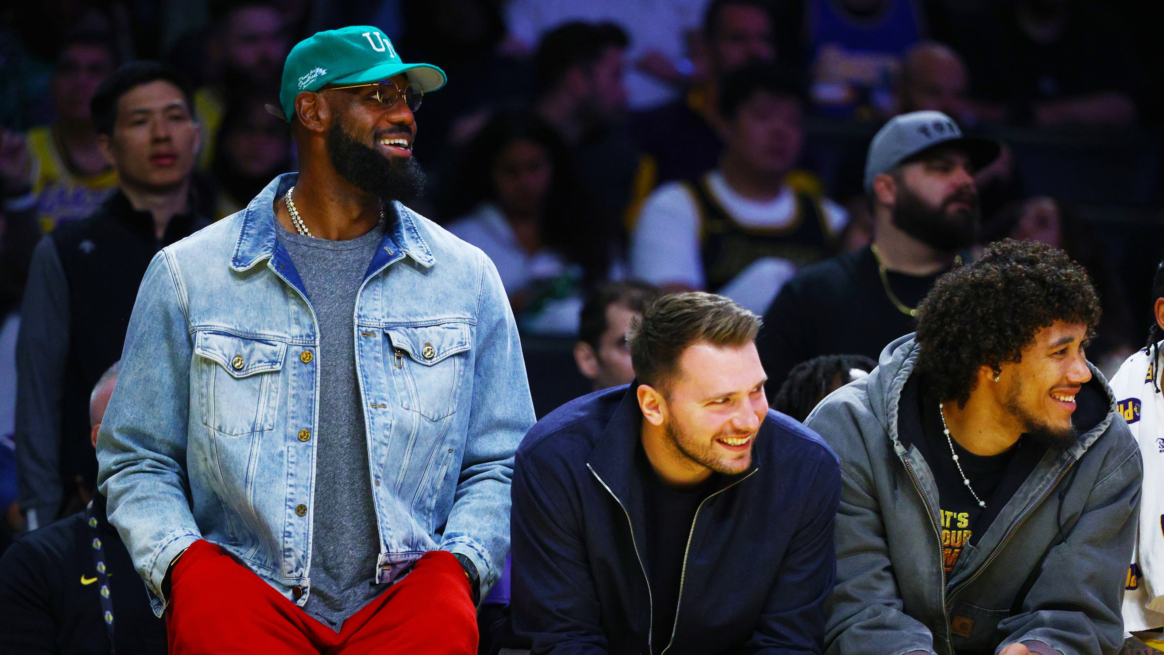 Los Angeles Lakers forward LeBron James (23) and Los Angeles Lakers guard Luka Doncic (77) watch from the bench during the second half of an NBA basketball game against the Portland Trail Blazers, Monday, Oct. 27, 2025, in Los Angeles. (AP Photo/Ethan Swope)