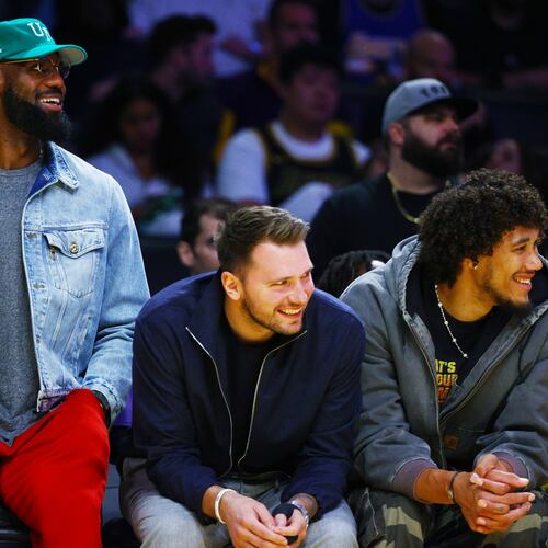 Los Angeles Lakers forward LeBron James (23) and Los Angeles Lakers guard Luka Doncic (77) watch from the bench during the second half of an NBA basketball game against the Portland Trail Blazers, Monday, Oct. 27, 2025, in Los Angeles. (AP Photo/Ethan Swope)