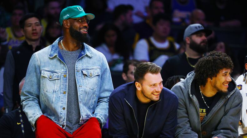 Los Angeles Lakers forward LeBron James (23) and Los Angeles Lakers guard Luka Doncic (77) watch from the bench during the second half of an NBA basketball game against the Portland Trail Blazers, Monday, Oct. 27, 2025, in Los Angeles. (AP Photo/Ethan Swope)