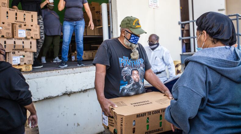 Volunteers, including Tracy Singletary, center with box, and Twinkle Lloyd, right, and Grace Community Fellowship Church staff distribute food boxes to multiple organizations who feed the homeless, elderly, immune compromised patients and those struggling with poverty Saturday, Nov 21, 2020.  Wednesday the group will be giving away boxed, hot turkey dinners and offering free covid testing, warm cloths and flu shots. (Jenni Girtman for The Atlanta Journal-Constitution)