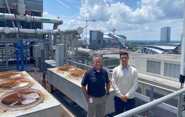 Jon Tibbitts (left) and Andrew Alves, of Digital Realty, pose atop the roof of 56 Marietta, a century-old building that serves as a downtown data center. (Zachary Hansen/AJC)