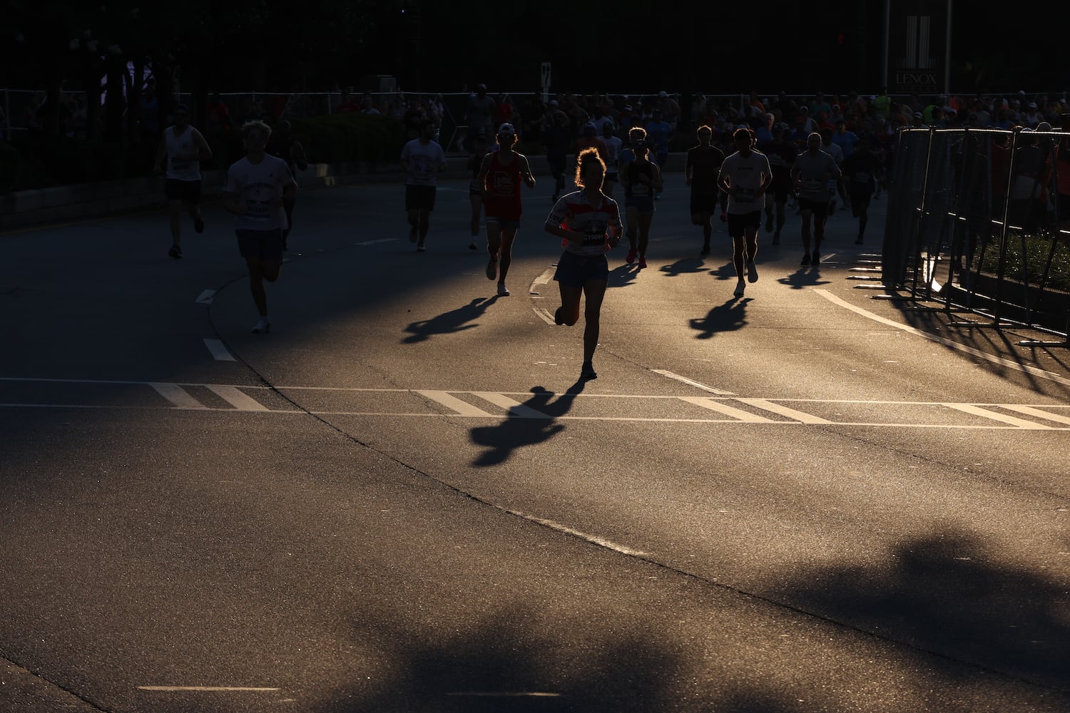 Runners run between shadows at the start of the 56th AJC Peachtree Road Race on Friday, July 4, 2025, in Atlanta. (Arvin Temkar/AJC)