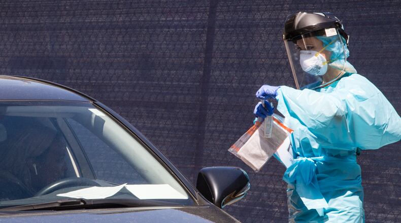 At the testing tent, Natalie Ali, a nurse volunteer puts a sample taken from the driver into a medical bag to be taken for testing Friday, April 3, 2020. Ethne Health in partnership with the City of Clarkston, community churches and food banks provides free covid testing for people showing symptoms who live in the Clarkston area. Results will take approximately 3 days before results will be know. The corona virus testing will continue on Saturday. (Jenni Girtman for the Atlanta Journal-Constitution)