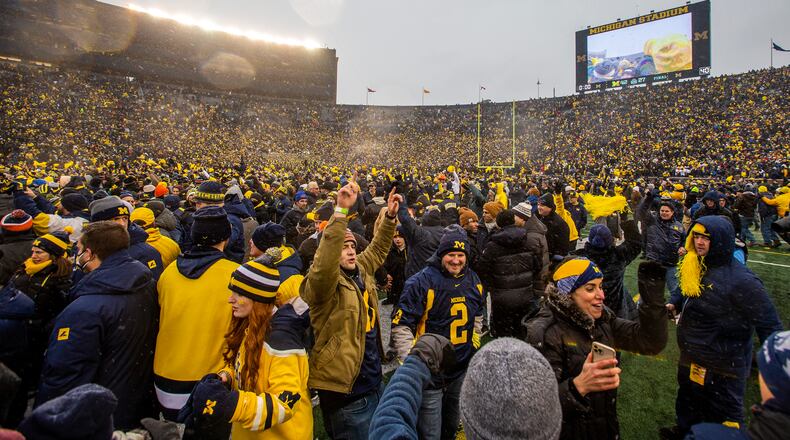 Michigan fans celebrate on the Michigan Stadium field after an NCAA college football game against Ohio State in Ann Arbor, Mich., Saturday, Nov. 27, 2021. Michigan won 42-27. (AP Photo/Tony Ding)