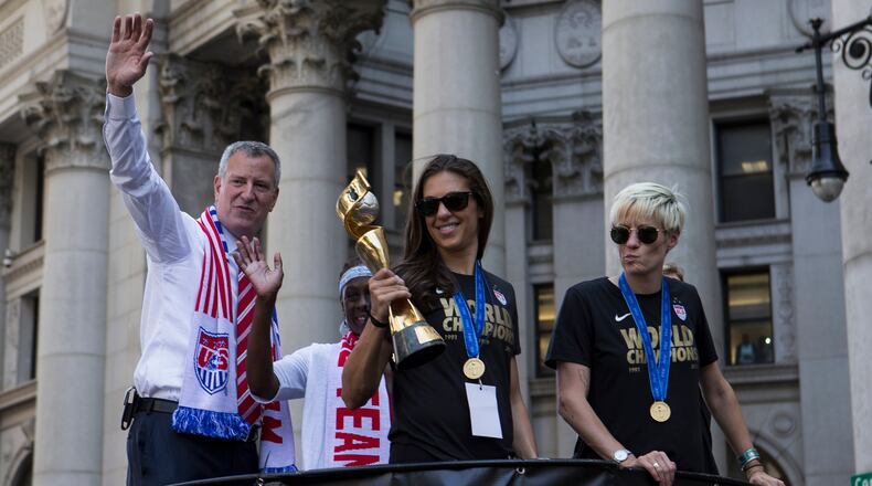 Carli Lloyd holds the World Cup trophy as she and other members of the U.S. women's national soccer team paraded down Broadway in New York, July 10, 2015. It's the first time the city has honored a women's sports team with a ticker-tape parade. At left is Mayor Bill de Blasio, at right, Megan Rapinoe. (Mark Kauzlarich/The New York Times)