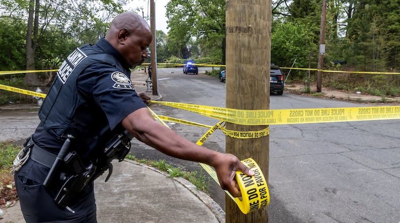 Atlanta police officer R. Mack stretches crime scene tape across Cooper Street on April 10 as police investigate a shooting in southwest Atlanta. (John Spink/The Atlanta Journal-Constitution)
