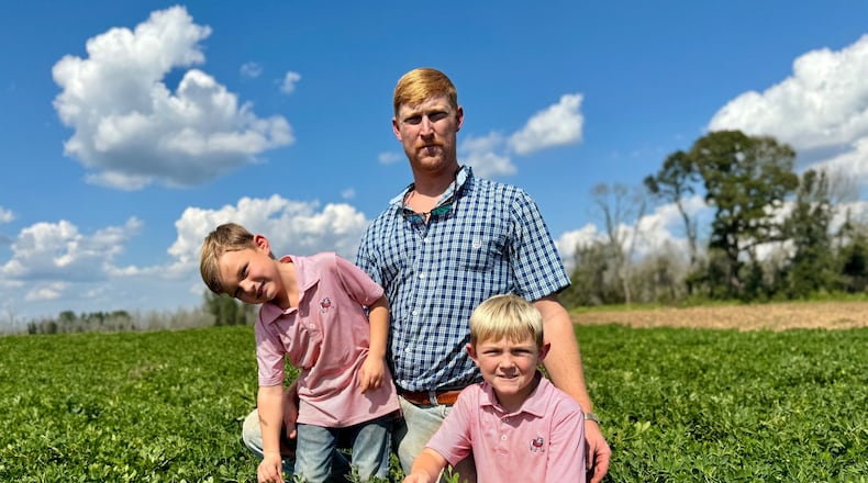 Peanut farmer Riley Davis sits in a peanut field along the Webster County border south of Plains with his sons, Drew (left), 4, and Luke, 7. (Joe Kovac Jr./AJC)