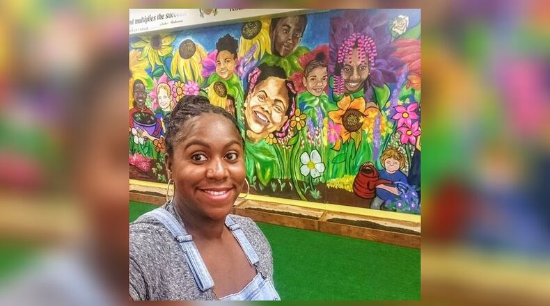 Ashley D. stands in front of her “Grow” mural painted on a wall at the Barack & Michelle Obama Academy in Atlanta.
