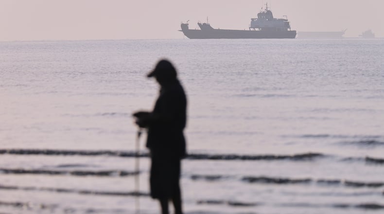 Cargo ships and service vessels are anchored in the Strait of Hormuz, as a person stands in shallow water, off Bandar Abbas, Iran, Sunday, May 31, 2026. (Amirhosein Khorgooi/ISNA via AP)