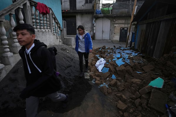 Neighbors walk past the rubble of a damaged house in Palin, Guatemala, Wednesday, July 9, 2025, after a series of earthquakes with magnitudes ranging from 3.0 to 5.6, according to authorities. (AP Photo/Moises Castillo)