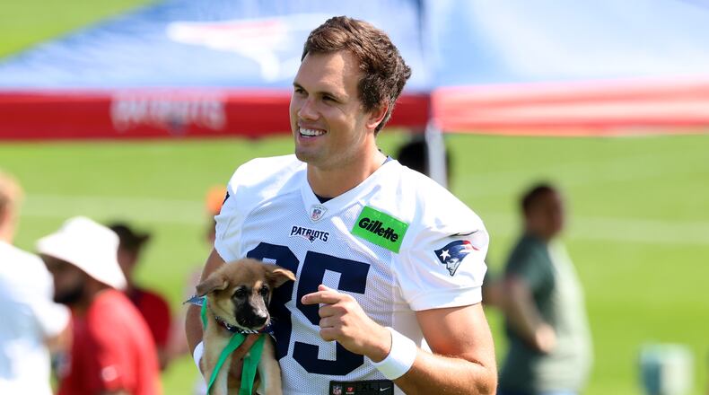 New England Patriots tight end Hunter Henry walks with a dog, part of the team's adopt a dog program at the team's first day of NFL football training camp, Saturday, July 25, 2026, in Foxborough, Mass. (AP Photo/Mark Stockwell)