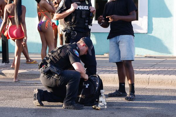 An officer searches the bag of an Orange Crush attendee following an altercation on Saturday, April 19, 2025. (Natrice Miller/ AJC)