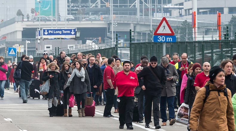 People walk away from the broken windows at Zaventem Airport in Brussels after an explosion on Tuesday, March 22, 2016. Explosions, at least one likely caused by a suicide bomber, rocked the Brussels airport and subway system Tuesday, prompting a lockdown of the Belgian capital and heightened security across Europe. At least 26 people were reported dead. (AP Photo/Geert Vanden Wijngaert)