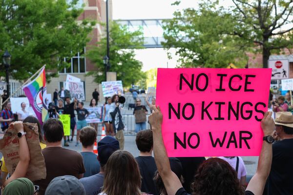 A protester holds a “No ICE, No Kings, No War” sign outside a Turning Point USA event in Athens in April, featuring Vice President JD Vance and Turning Point USA CEO Erika Kirk. (Felix Scheyer for the AJC)