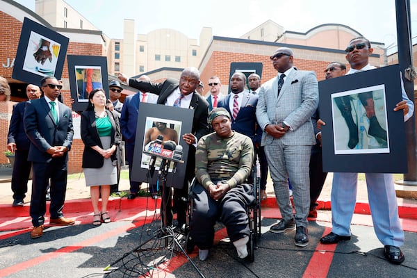 Civil rights attorney Ben Crump (center left), his legal team and other supporters of Rashaad Muhammad (seated) speak to reporters outside the Fulton County Jail on Wednesday. (Miguel Martinez/AJC)