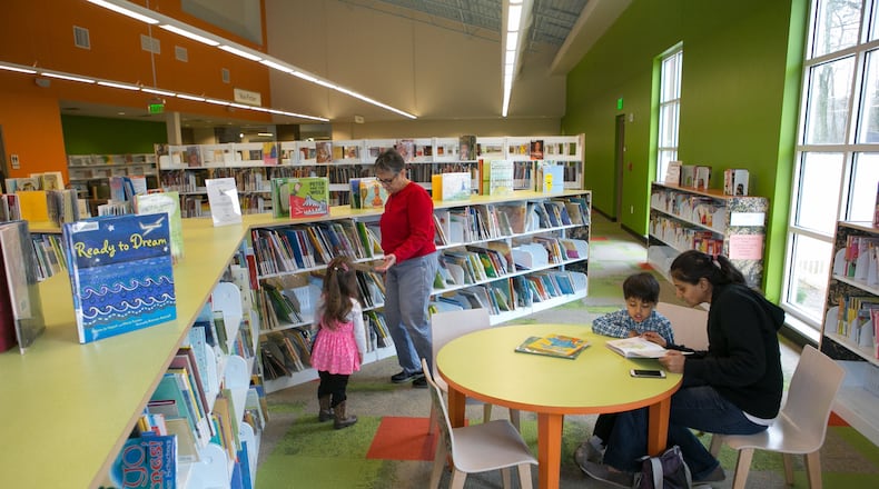 In this file photo, Margarita Sleeper of Roswell and her granddaughter Emma Racine (left), 2, choose a book as Divya Patel (right) of Milton reads a book to her son Nikhil, 4, in the Children’s Book section at the Milton Library. This location will remain open as other Fulton County libraries close for renovations.