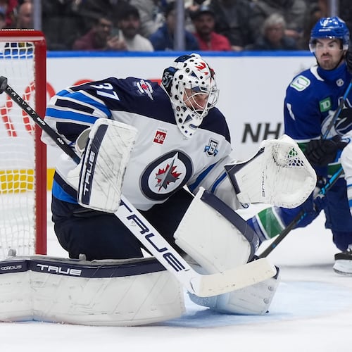 Winnipeg Jets goalie Connor Hellebuyck (37) makes a save with the shaft of his stick during the third period of an NHL hockey game against the Vancouver Canucks, in Vancouver, on Tuesday, Nov. 11, 2025. (Darryl Dyck/The Canadian Press via AP)
