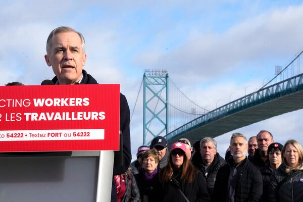 Unifor auto workers stand behind Liberal Leader Mark Carney as he speaks during a campaign stop at the Ambassador Bridge in Windsor, Ont., on Wednesday, March 26, 2025. (Frank Gunn /The Canadian Press via AP)